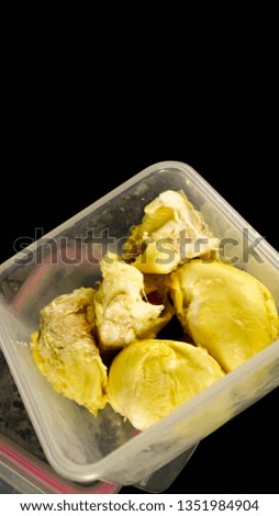 close up of creamy durian fruit inside plastic container isolated in black 