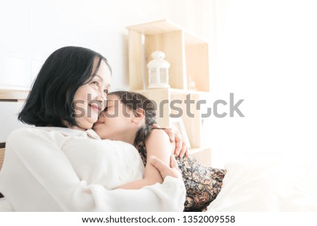 old asian female hug asian children on white bed, old asian woman talk about tale to her daughter in family time, mother day, retirement happiness, elderly activity, mother day
