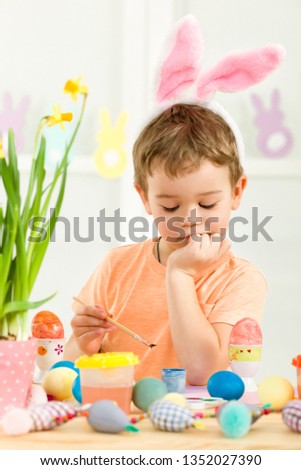 little child boy with Easter bunny ears painting Easter eggs at home. adorable child prepare for easter. Happy easter