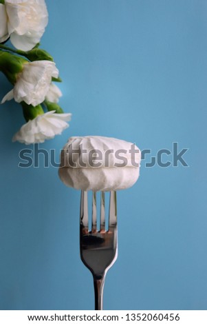 Marshmallow on a fork. Bright dessert. Blue background with empty place for text