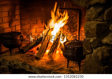 Cooking food on fire in an old fireplace. Bake food in the oven in a cast-iron metal dish. Grill on fire. Bonfire, fire in the fireplace.