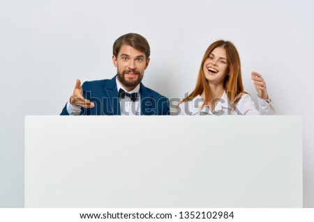 A woman and a business man are standing behind a white drawing paper