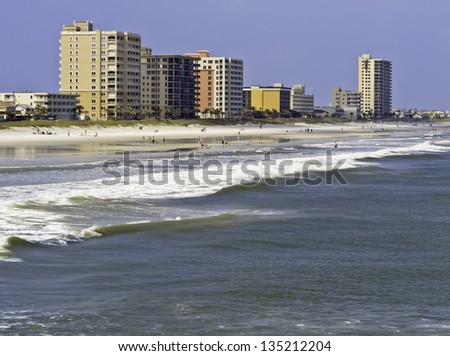 Vacation lifestyle: Surf, sand, and high-rise skyline along shore of Jacksonville Beach, Florida, on a sunny afternoon