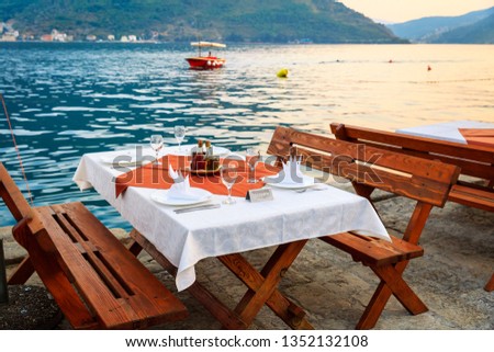 Reserved table with a white tablecloth, glasses and plates for a romantic dinner in a restaurant on the beach on vacation. Celebration. Party. Travel. Catering