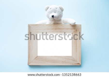Photo old wood frame with single white teddy bear sitting on blue background. copy space for text.
