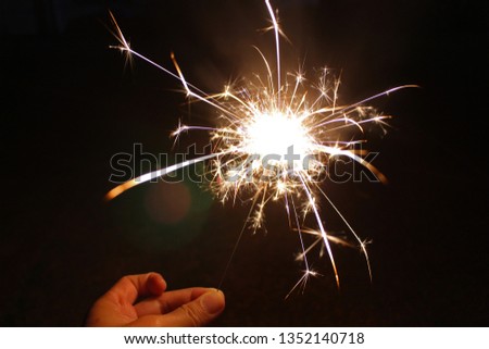 Hand holding a burning sparkler firework