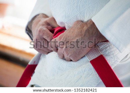 Hands of an elderly coach with a red-white judo belt and kimono Royalty-Free Stock Photo #1352182421