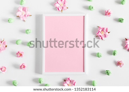 Easter decor, composition. Blank frame for text, flowers, easter eggs on white background. Flat lay, top view, copy space