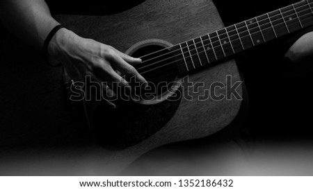 Close-up of the hands of a musician playing the guitar. The fingers of the musician are pressing the strings on the guitar