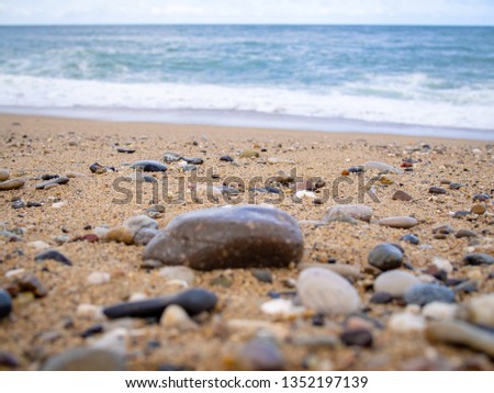 Pebbles on the beach close up on the sea surf background, copy space