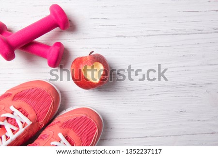Pink dumbbells, training shoes and apple with heart, fitness concept, healthy lifestyle, top view