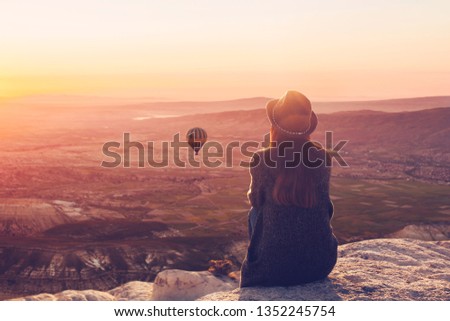 A woman on top of a hill alone admires the tranquil natural landscape and balloon and enjoys silence in Cappadocia in Turkey Royalty-Free Stock Photo #1352245754