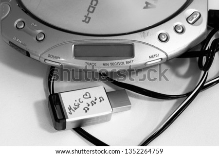 Open portable Cd player and a USB flash drive with a written label with the word "music" 