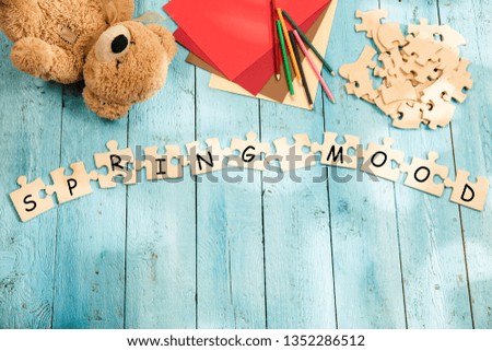 Stationery and words SPRING MOOD made of letters, mock up and pieces of puzzles on wooden background. Concept of family, parenting, children, rest, travel, school break.