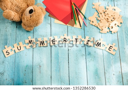 Stationery and words SUMMER TIME made of letters, mock up and pieces of puzzles on wooden background. Travel concept. Summer vacation concepts.