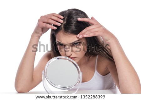 Young girl in shock of her acne. Photo of ugly girl with problem skin looking at mirror.  Skin care concept 