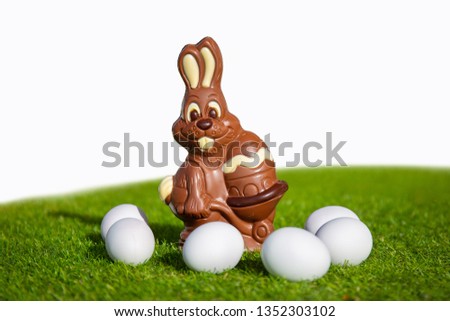 Decoration for the Easter with a chocolate Bunny on grass with white eggs und a white background