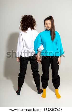 Fashionable Caucasian young female women wearing stylish clothing laughing happily, having fun in photo studio. People, youth, leisure and lifestyle concept. Copy Space