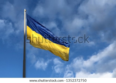 Blue and yellow Ukrainian national flag on a flagpole against a blue cloudy sky. the symbol of presidential elections in Ukraine 2019. 
