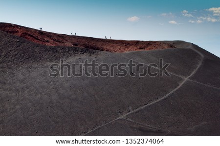 People hiking and walking near volcano craters on Mount Etna, active volcano on the east coast of Catania, Sicily, Italy. Landscape of Etna volcano, Deserted martian-like surface. Travel photography.