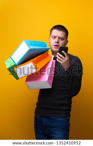 Photo of man with phone and multi-colored shopping bags