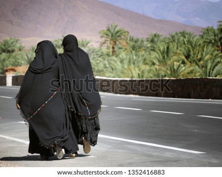 Two women walk down  the road in the oasis 
