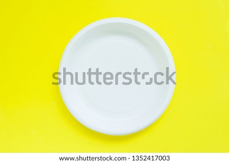 Disposable plastic plates on bright yellow background with copy space