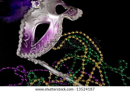 A purple "Mardi Gras" mask or face covering with bead necklaces on a black background