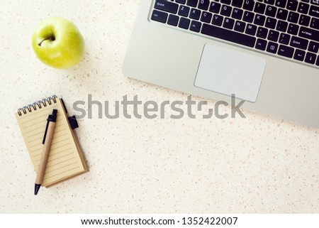 top of desk with notebook pen green apple and laptop keyboard