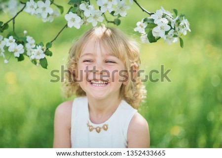 girl sniffing flowers of apple orchard. garden with flowering trees. Allergy season