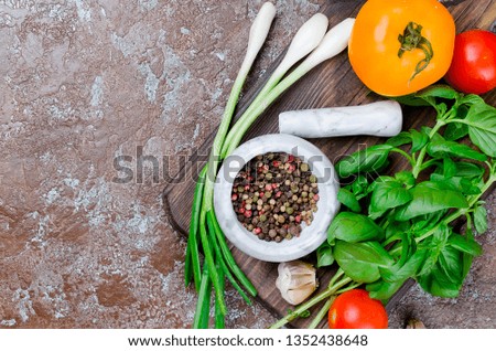 Ripe red and yellow tomatoes, green onion and basil, garlic, salt  and spices on a dark stone  background. Top view, Copy space. 