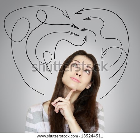 Young woman thinking and looking up with many arrows above the head on grey background