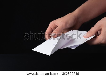 white envelope in a female hand on black background