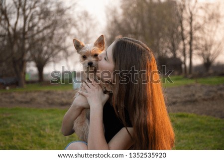 Teenage girl kissing her cute puppy during a walk through the meadow.