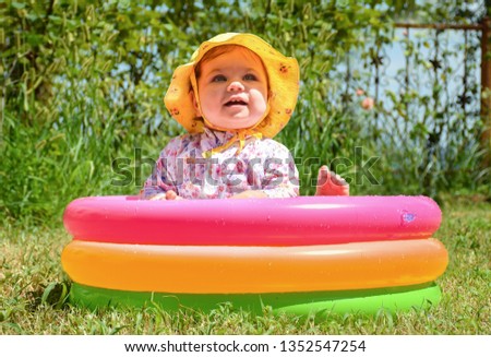 Portrait of little girl play with water in swimming pool. Toddler child have fun in sunny summer garden with inflatable pool. Kid play outdoors. Sweet family time and Happy childhood concept.