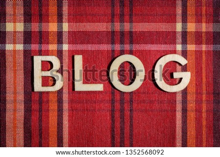 Blog word written with wooden letters on red textile material with colored stripes, top view, flat lay
