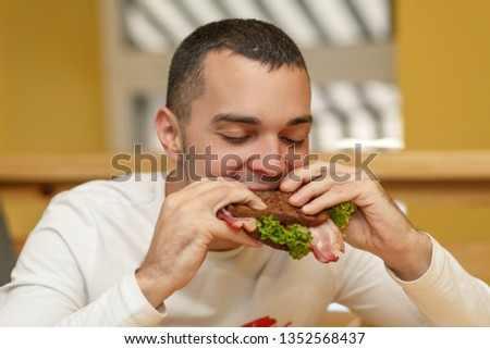 Hungry young man in resaurant eat sandwich.