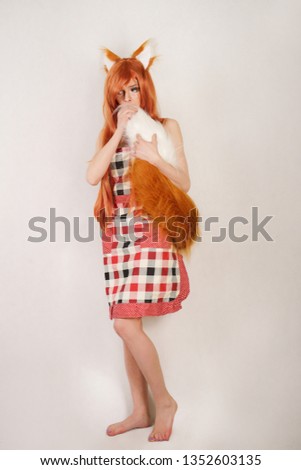 redhead girl with fur ears and tail posing in kitchen apron on white background in Studio