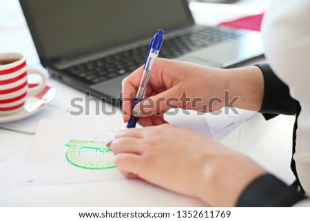 Young businesswoman sitting at table with modern laptop at home and writing and processing photos.-Image