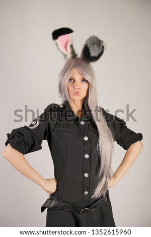 teen girl in FBI black carnival dress with big fur rabbit ears loves cosplay and stands on white Studio background