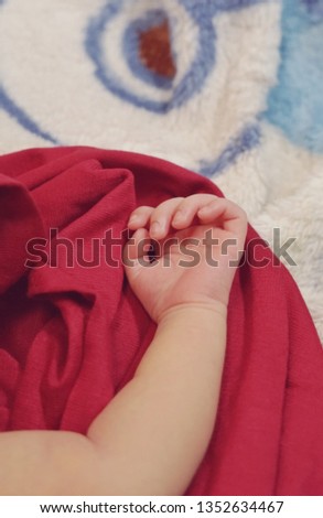 photo of a newborn baby's hand on a red cloth.