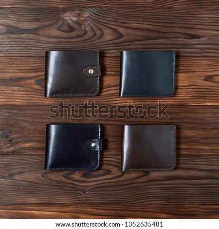 Four handmade leather gloss wallets on wooden textured background. Up to down view. Businessman wallet stock photo.