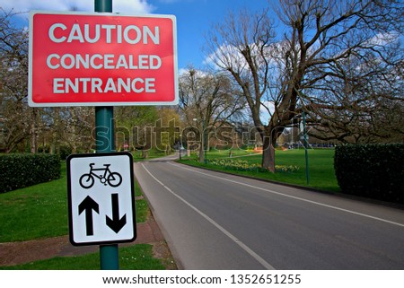 Road sign Caution Concealed Entrance and cycles both directions sign, blue cloudy sky.