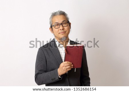 The Asian man showing note book on the white background.