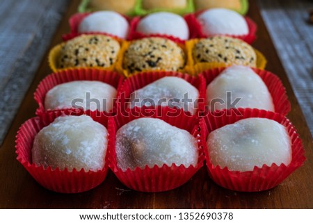 Assortment of colorful moon cakes, rice cakes, mochi cream arranged on a wooden table