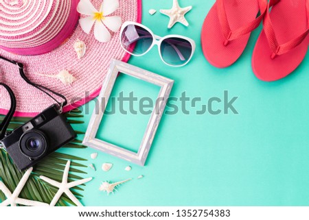 Beach accessories retro film camera Picture Frame, sunglasses, flip flop, starfish beach hat and sea shell on bright pastel green background for summer holiday and vacation concept.