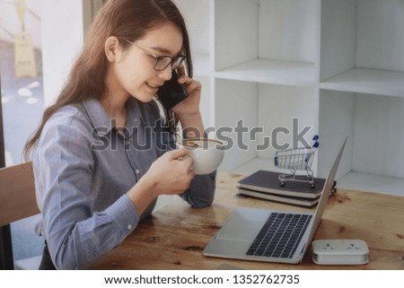 Young business woman drinking coffee on working and using smartphone on desk place at the office.