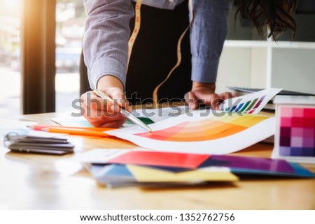 Young fashion designer women looking sample color with sketches on desk working on her.  Personal Fabrics fashion designer concept.