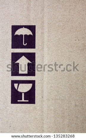 Black fragile symbol on cardboard, brown paper box.