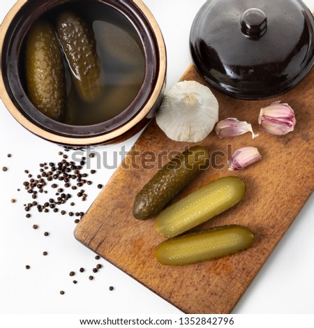 Pickled cucumbers, pepper, garlic, and a stone pot. Sliced cucumbers on a wooden board.. White background. Pictures of vegetables for the website. Polish cuisine. 